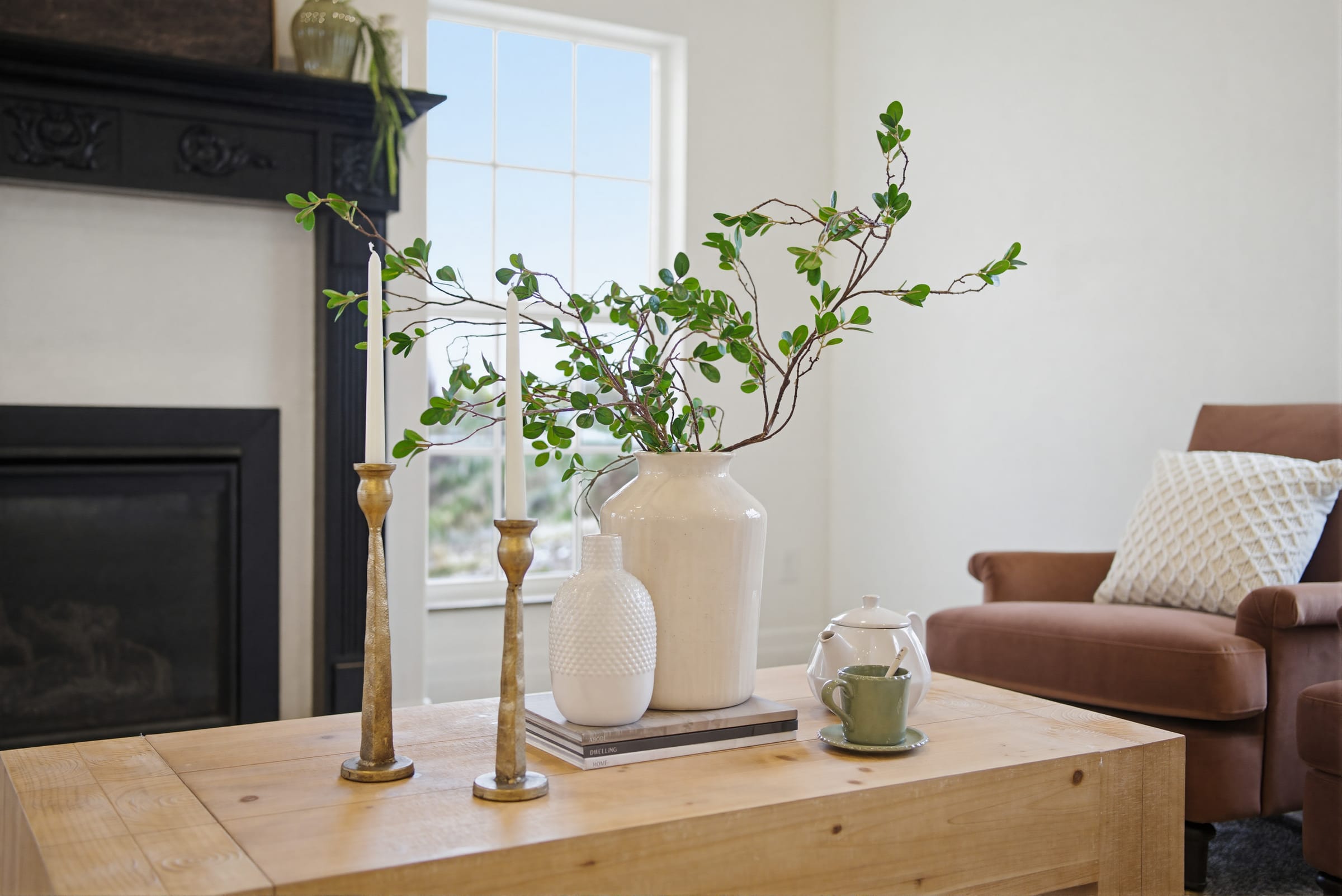 A styled tabletop vignette with a vase of branches and candlesticks