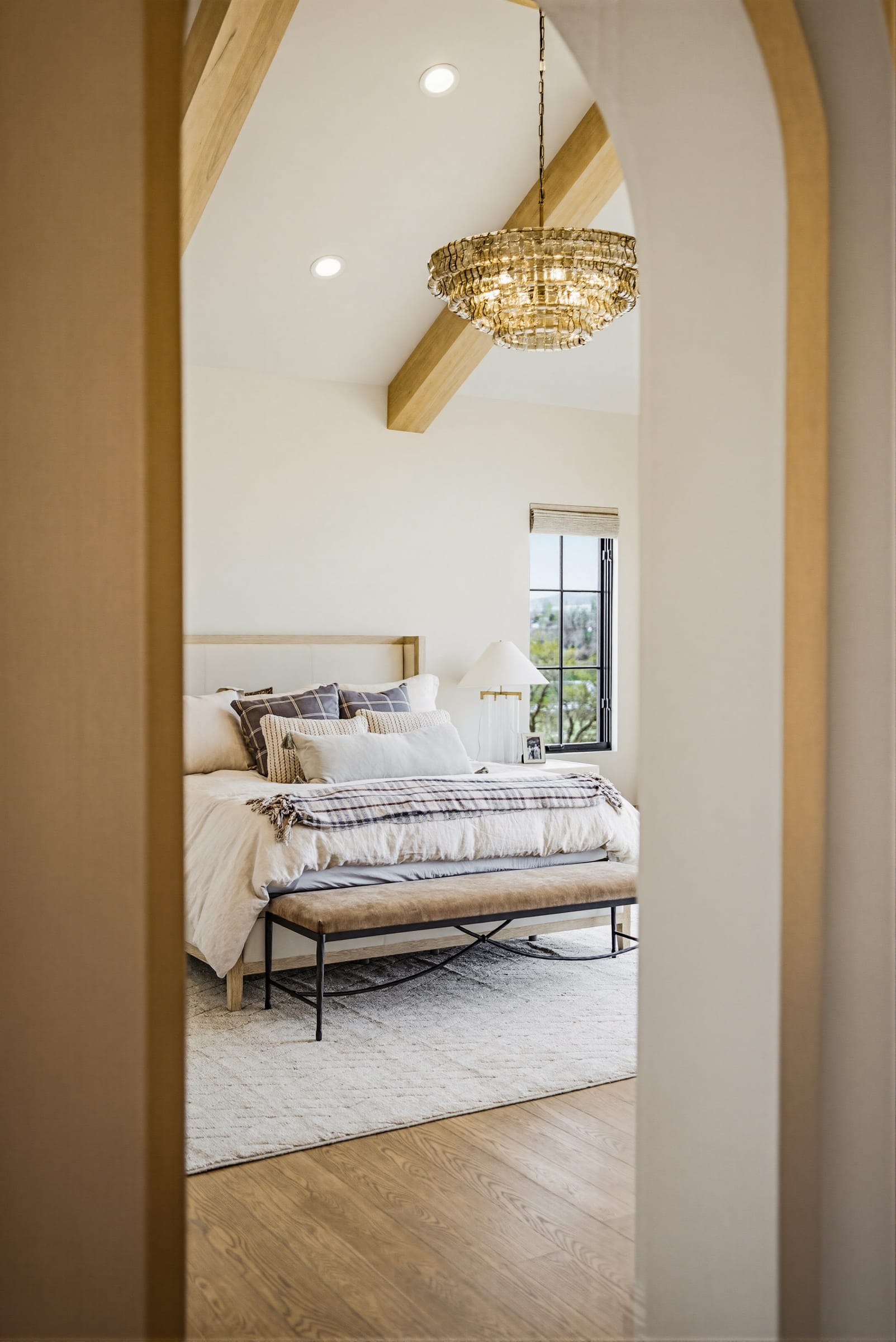 A vaulted primary bedroom seen through an arched doorway